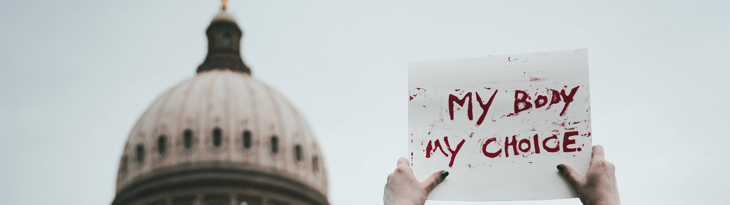 a protest scene on the right with a person holding a sign reading "My Body, My Choice" in front of a government building